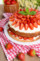 Delicious biscuit cake with strawberries on table close-up