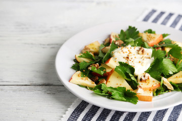 Green salad with apples, walnuts and cheese on wooden