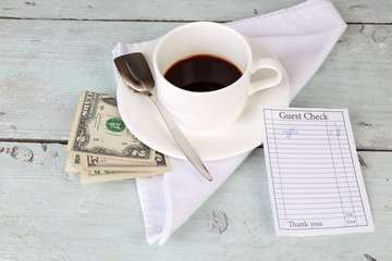 Check, money and cup of coffee on table close-up