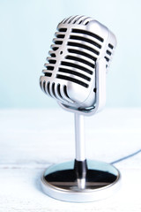 Vintage microphone on table on light blue background