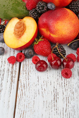 Peaches with berries on wooden table close-up