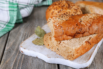 Fresh baked bread on cutting board, on wooden background