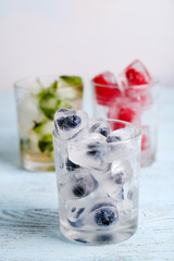 Ice cubes with mint leaves, raspberry and blueberry in glasses,