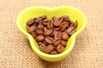Coffee grains in cup on jute canvas