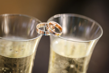 wedding rings lie on champagne glasses