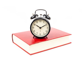 Naklejka premium alarm clock on red textbook on white background