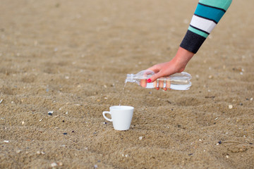 coffee cup on the sand and water bottle