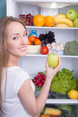 Woman choosing apple in refrigerator full of tasty organic