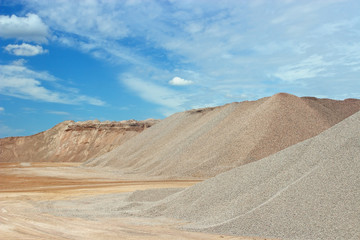 Sand heaps with blue sky in gravel quarry