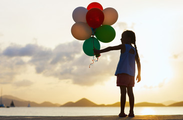 Happy girl with balloons at sunset