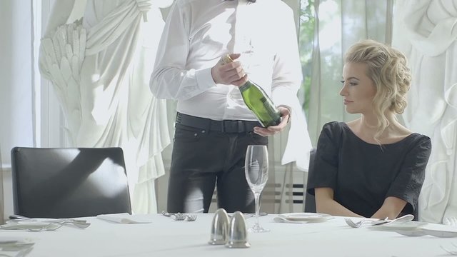 Young blonde woman selecting wine in luxury restaurant table