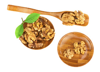Handful of walnuts in wooden bowls, scoop and green leaves isola