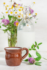 Fresh milk in ceramic mug and wildflowers