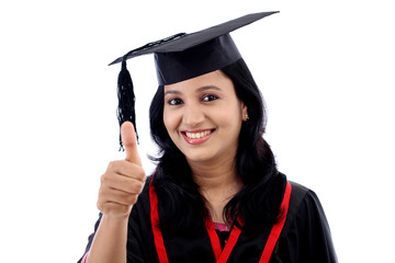 Smiling young graduation student making thumbsup gesture