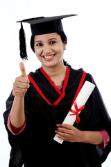 Smiling young graduation student making thumbsup gesture