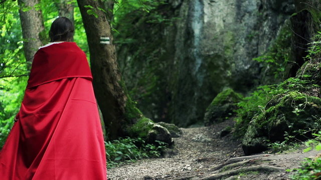 Mysterious red riding hood walking in forest, super slow motion