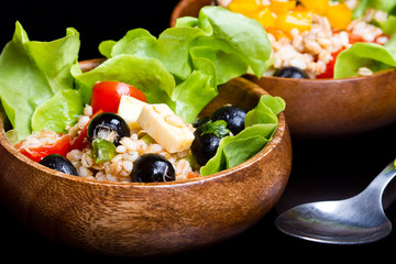 wood bowl with spelt salad with olives and tomatoes