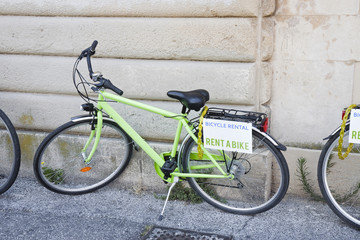 Fototapeta na wymiar Green bicycle for rent against the wall