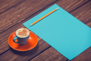Cup of coffee and pencil with paper.