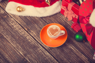 Cup of coffee with heart shape with christmas gifts.