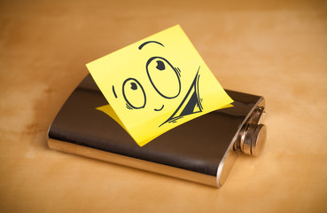 Post-it note with smiley face sticked on hip flask