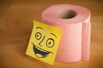 Post-it note with smiley face sticked on a toilet paper