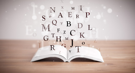Opened book with flying letters