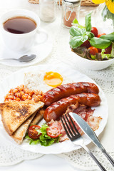 Full English breakfast with bacon, sausage, fried egg and baked