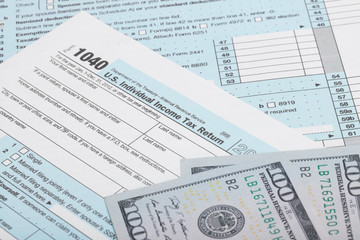 US 1040 Tax Form with two 100 US dollar bills over it