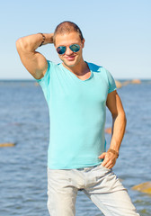 Muscular attractive man in glasses near the sea.