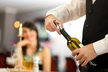 Kellner entkorkt eine Weinflasche in einem Restaurant