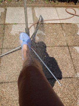 Mit einem Bein unter der Gartendusche