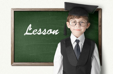 Cheerful little boy on blackboard. Looking at camera