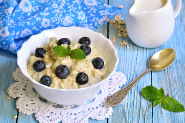 Oatmeal porridge with blueberry in a white bowl.