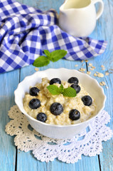 Oatmeal porridge with blueberry in a white bowl.