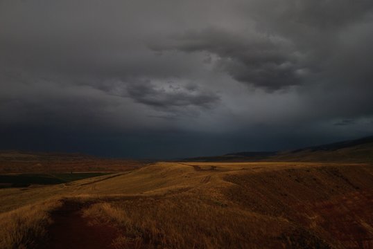 landscape of road between fields in thunderstorm