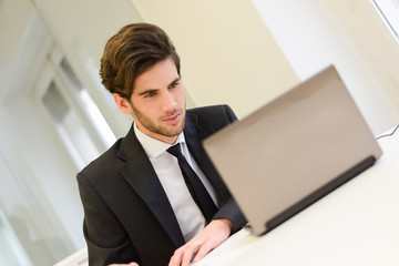 Businessman sitting at his laptop and working in his office