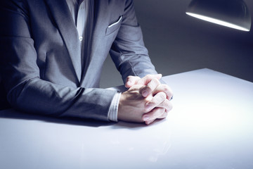 close up of a man in a suit with his hands clasped in front