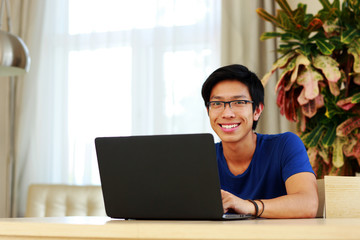 Fototapeta premium Happy asian man sitting at the table with laptop