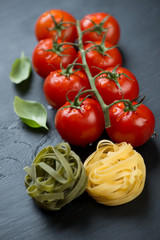 Close-up of red tomatoes, tagliatelle and green basil leaves