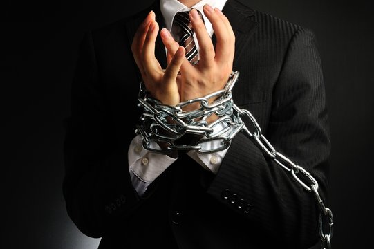 手を鎖で縛られたビジネスマン