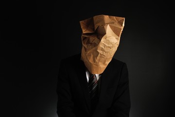 紙袋で顔を隠したスーツのビジネスマンの気分が落ち込んでいる様子