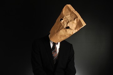 紙袋で顔を隠したスーツのビジネスマンの気分が落ち込んでいる様子