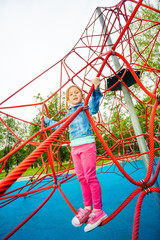Pretty girl standing on red net of playground