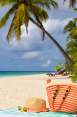 hat, bag, sun glasses and flip flops on  the beach