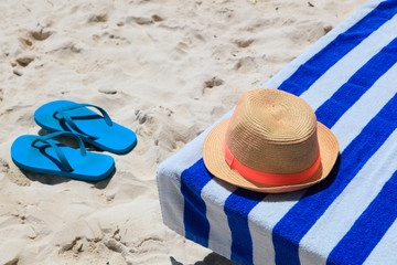 Straw hat, towel and flip flops on a tropical beach