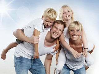 Parents giving piggyback ride to children outside