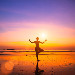 Fototapeta na wymiar Yoga woman on sea coast at sunset.