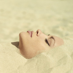 Fototapeta premium Beautiful lady buried in the sand