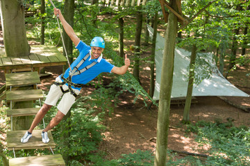 Man climbs over obstacles at high rope court